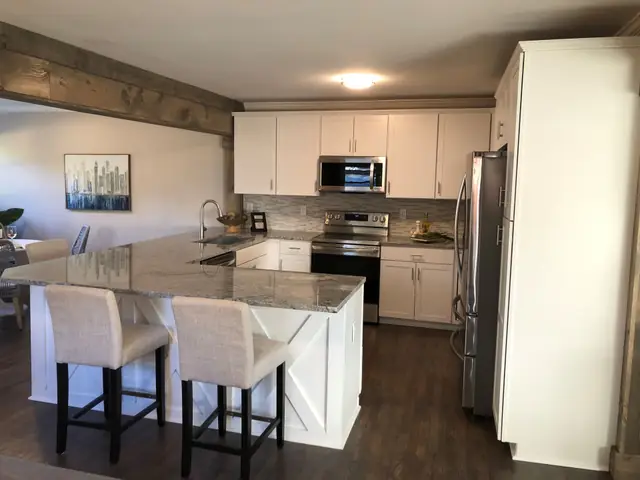 White kitchen with a center island and bar stools, pendant lights over the counter