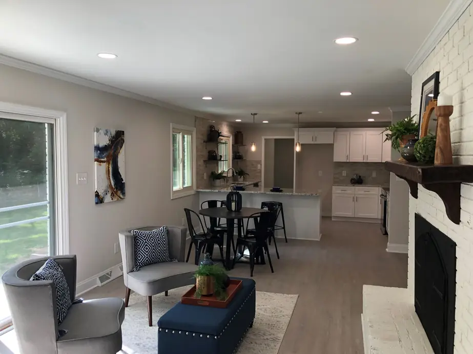 Open kitchen and living room with a fireplace, finished in white and warm wood