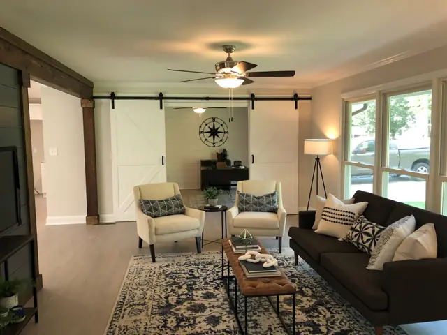 Living room with sliding barn doors, an exposed wood beam and a sectional sofa